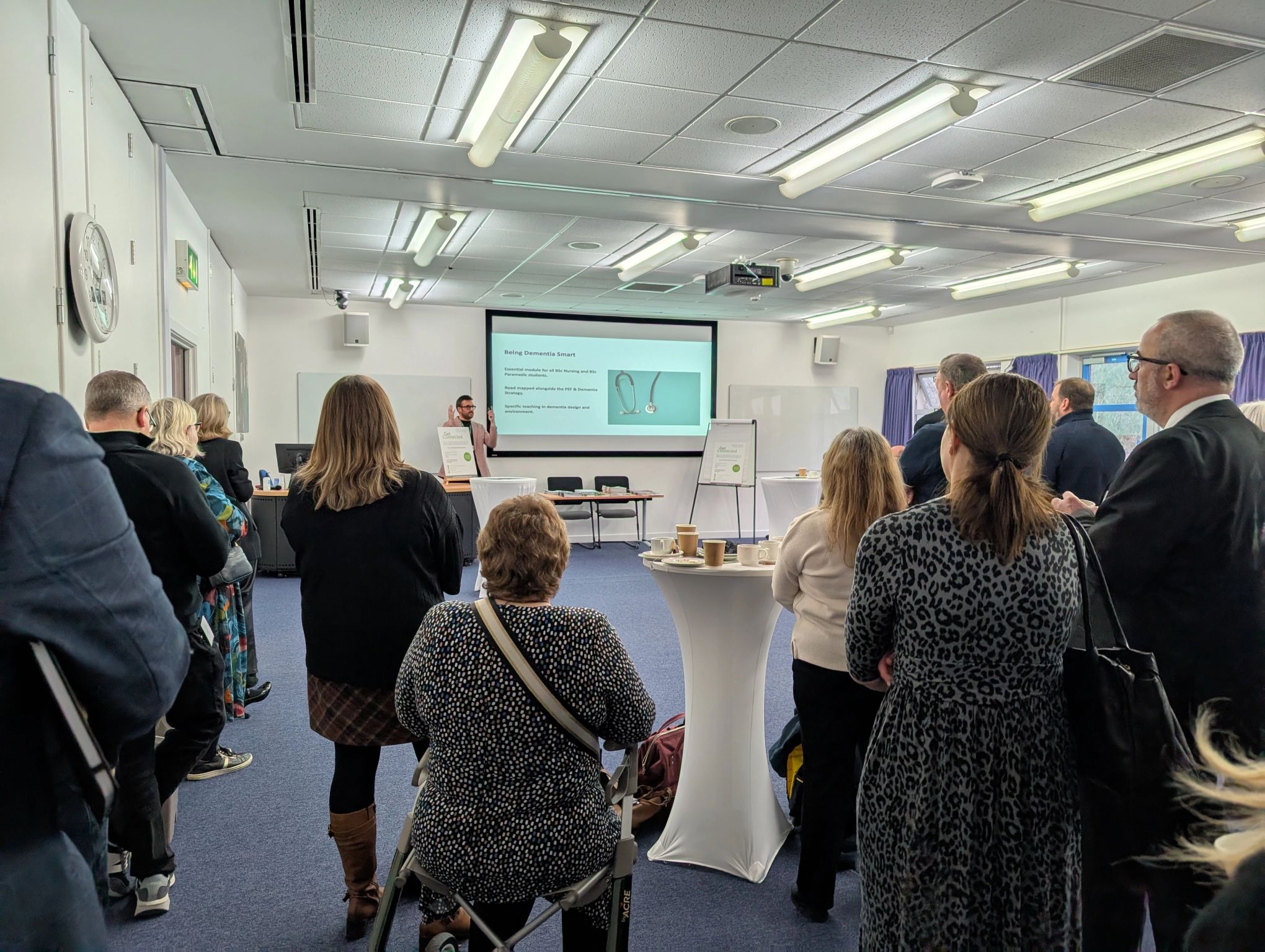 MPFG workshop participants engaged in professional presentation with projection screen and flip charts